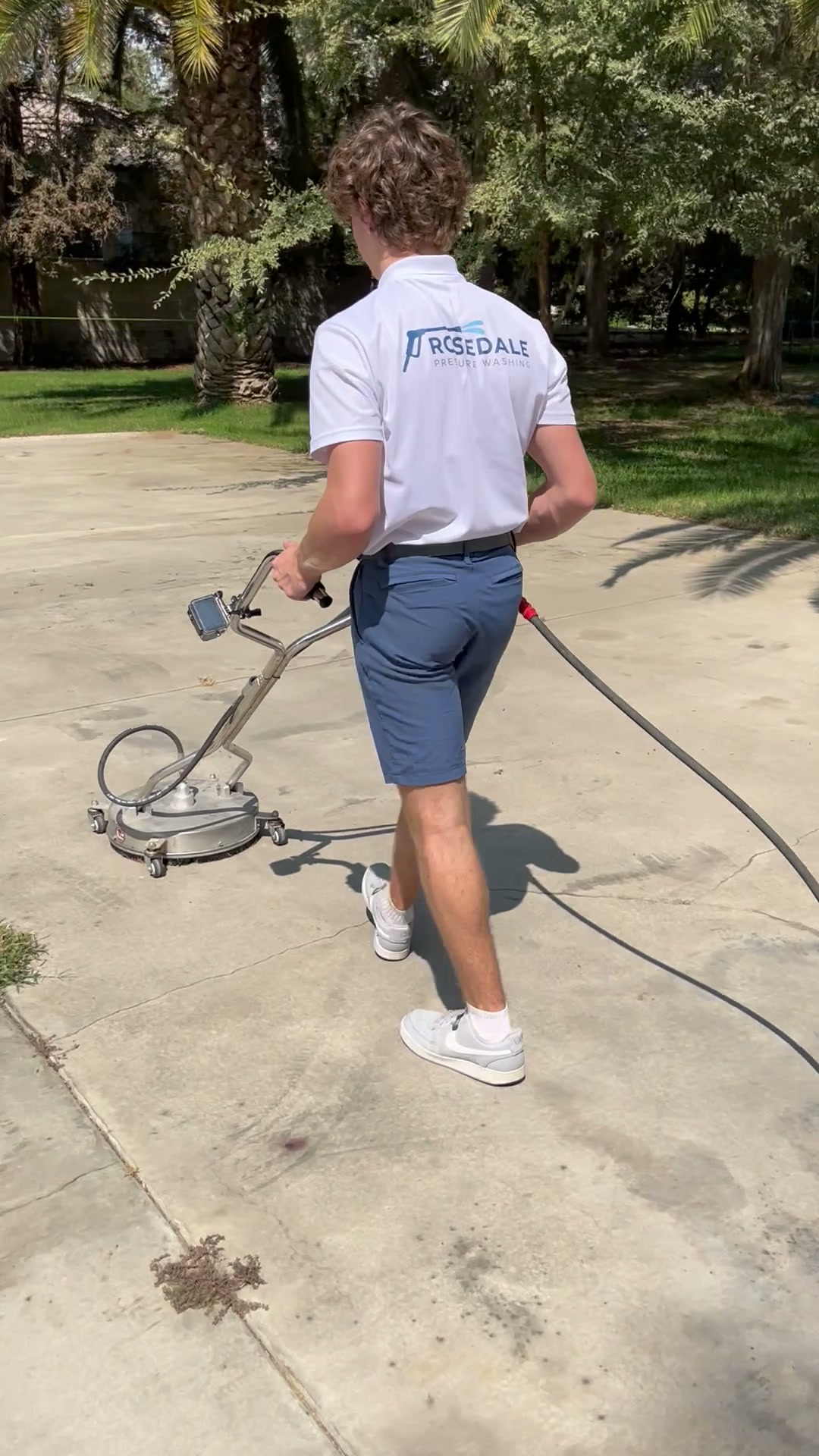 Liam using a surface cleaner with the Rosedale Pressure Washing logo visible on his shirt
