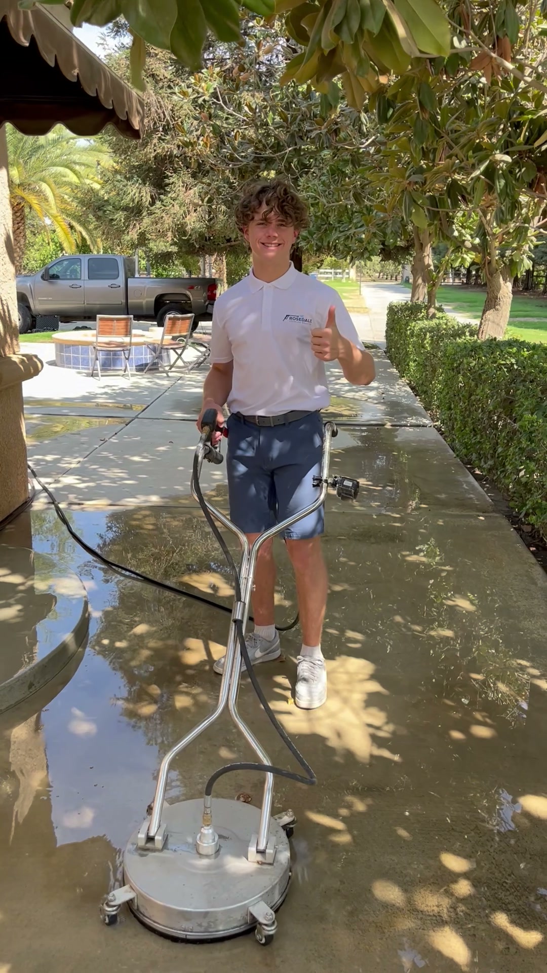 Liam of Rosedale Pressure Washing smiling while working with a surface cleaner